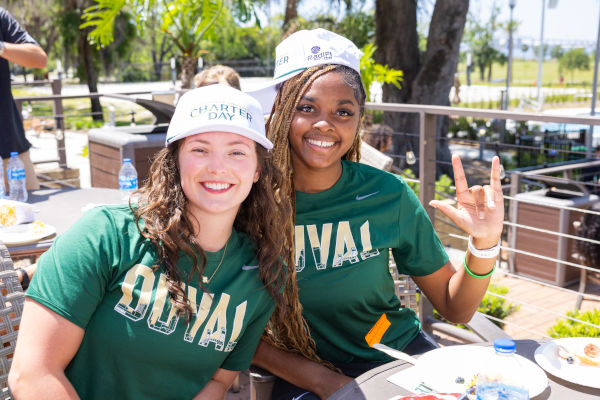 Two smiling Jacksonville University students wearing green