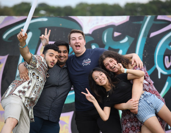 A group of young students signaling the V of victory with their hands