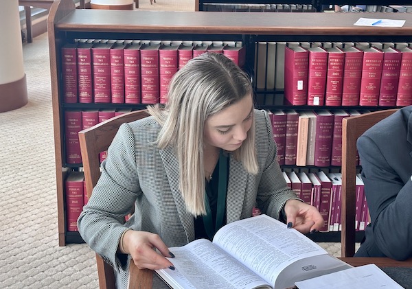 A female student sitting at a desk, reading a book.