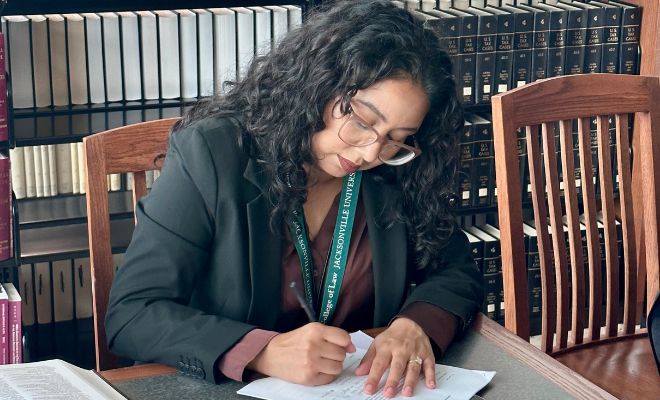 A female student sitting a desk and working in a book.