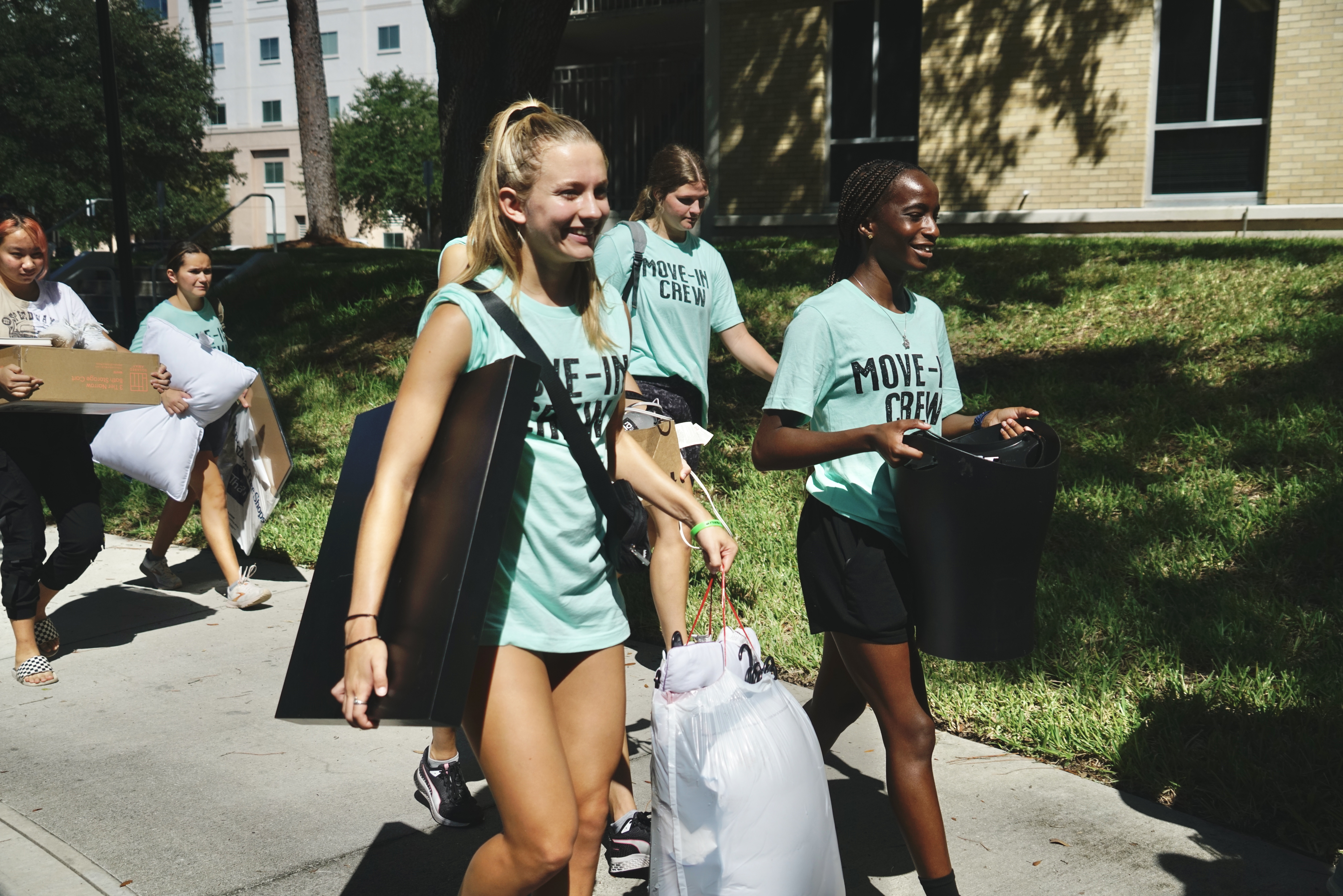  Smiling students help carry items inside during move-in.