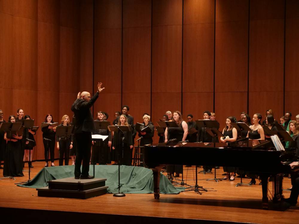 Combined choirs at Jacksonville University wearing all black and green scarves