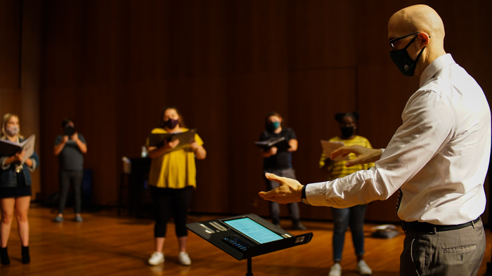 Choral students and Choral Director, Dr. Julian Bryson, practicing a musical piece.