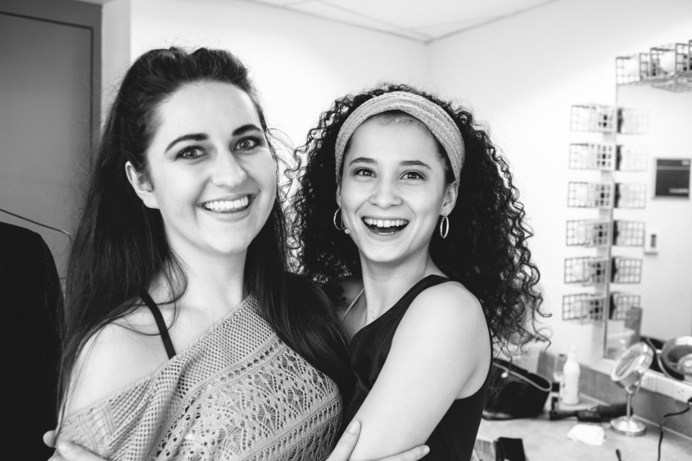 Two cast members backstage smiling.