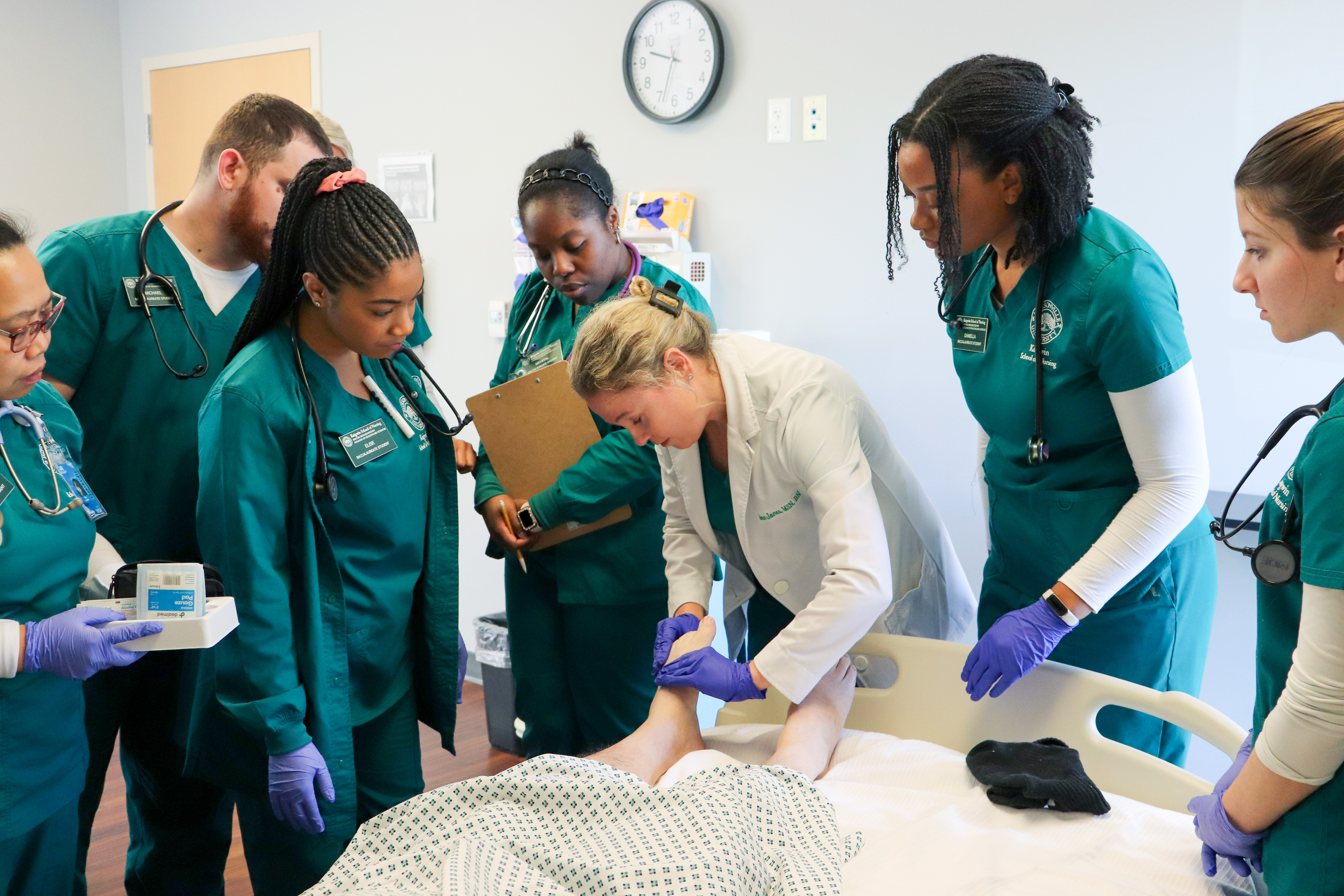 Nursing faculty with students and patient