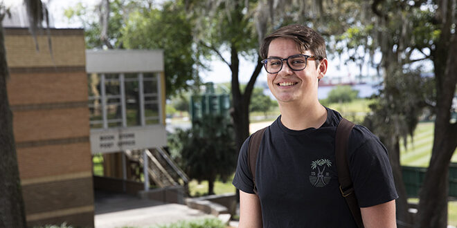 A male student smiling in front of JU's Kinne Center.