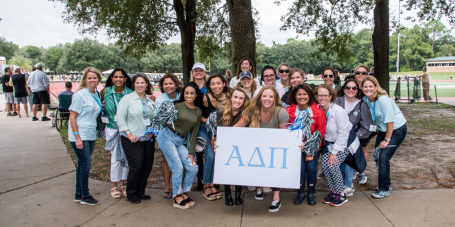 A group of JU Greek Life members holding a sorority sign while they pose for a photo.