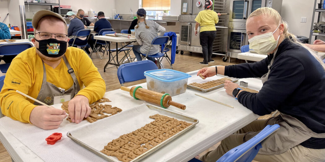 Students sitting at a table, making dog biscuits