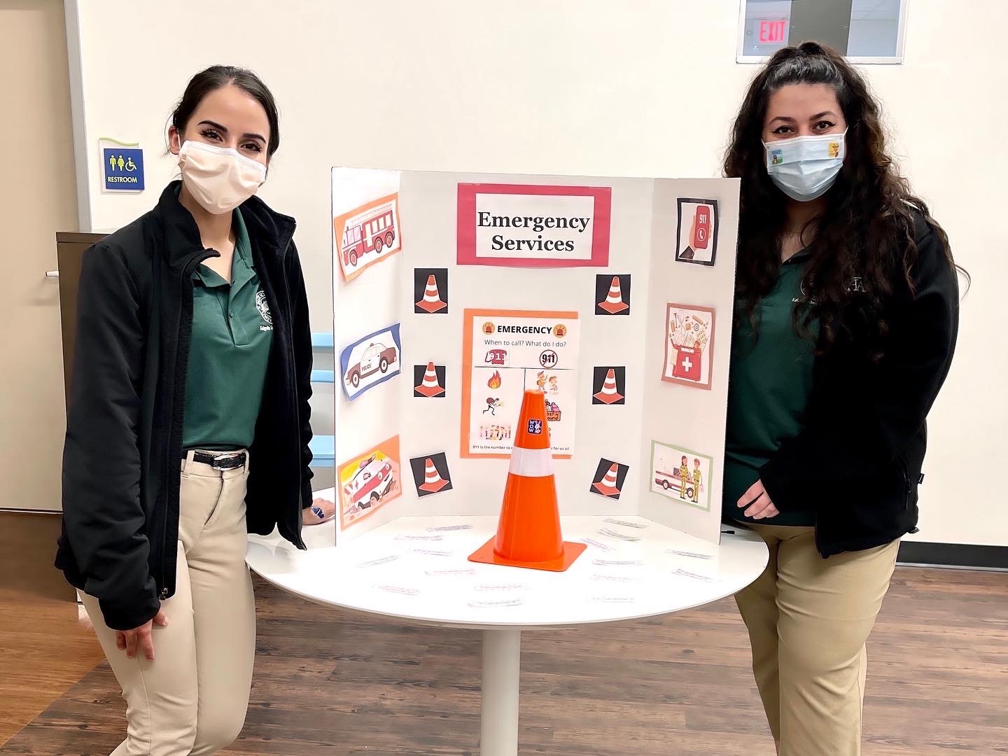Two female students standing with a poster-board presentation on Emergency Services