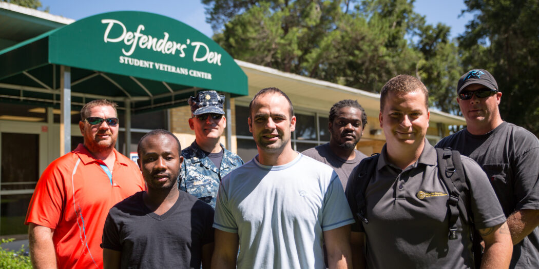 A group of veteran and active duty students standing in front of the Defender's Den.