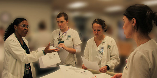 Nursing students listen to instructor during a patient simulation with a medical manikin