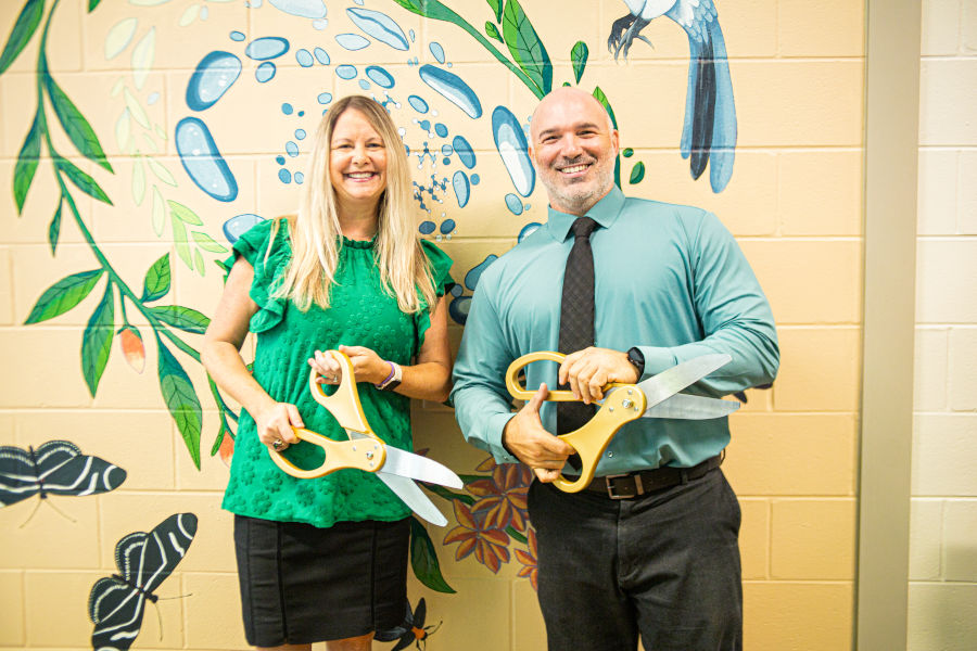 Dr. Bill Penwell and Dr. Kara Conway hold ribbon-cutting scissors