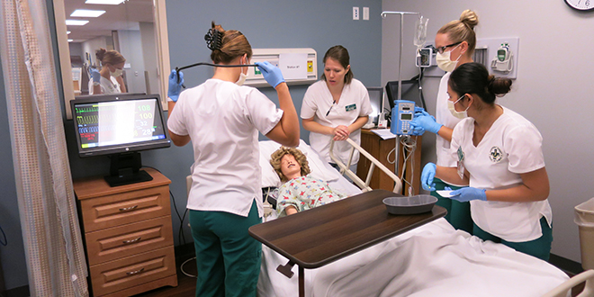 A group of nursing students working in a simulation setting with a model patient.