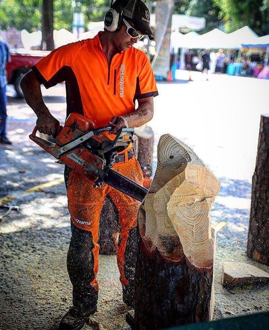 A main holding a chainsaw, carving a wood sculpture.