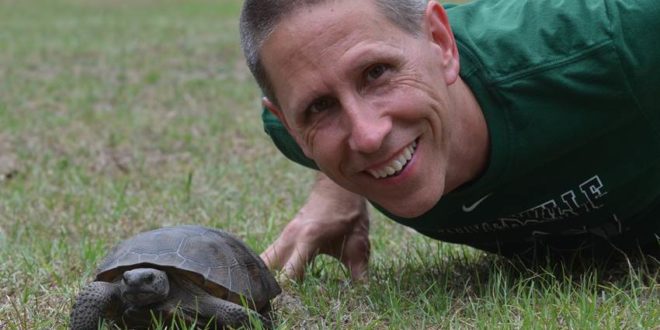 Dr. Enz smiling with a tortoise. 