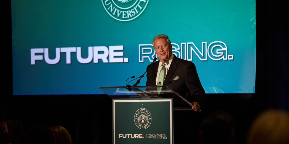 President Cost speaking at a podium