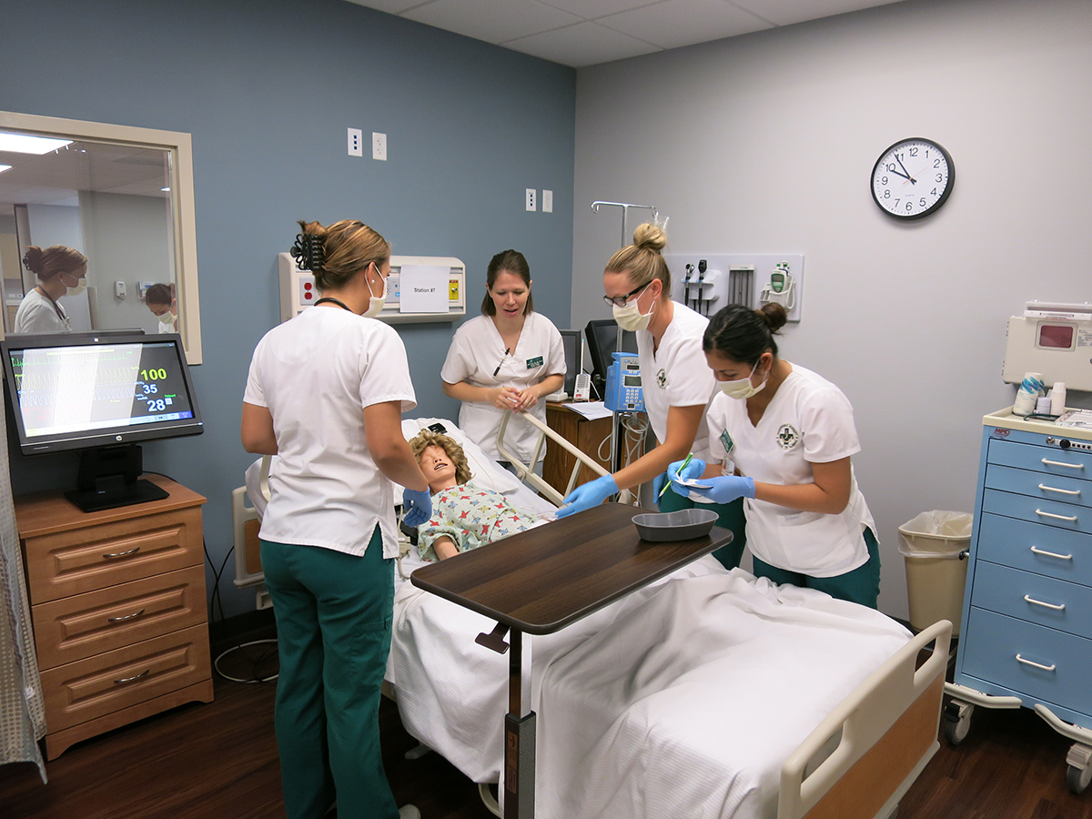 four female nurses perform a patient simulation on a medical manikin
