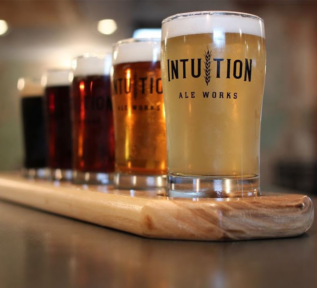 A flight of beers in pint glasses that read "Intuition Ale Works."