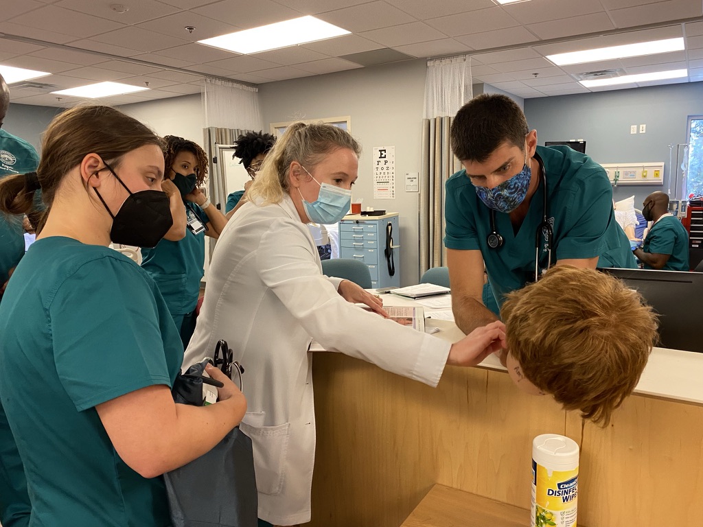 Three nursing students working on a mannequin patient. 