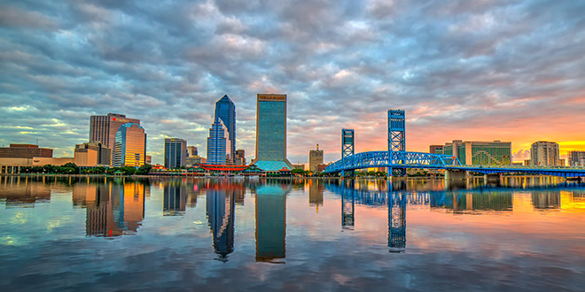 Photo of the Jacksonville skyline and the St. Johns River at sunset on a cloudy day