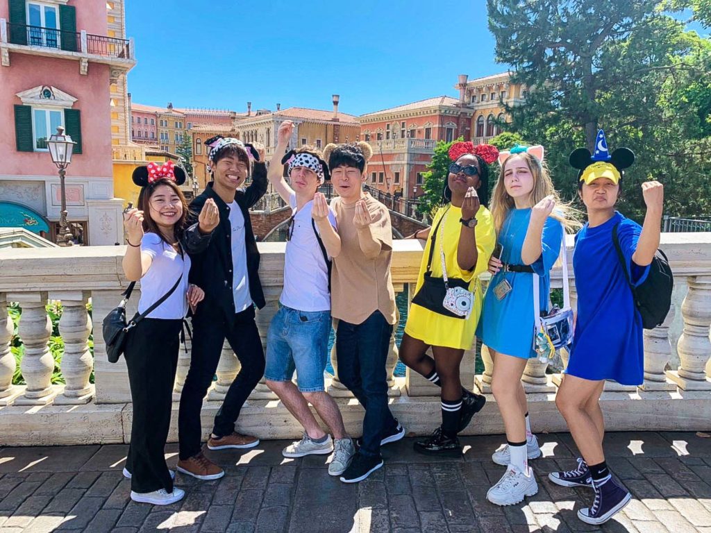 A group of JU students studying abroad with Japanese residents posing at Tokyo Disney