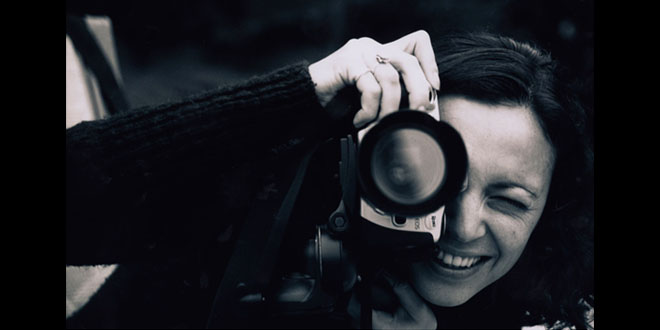 Marcia Brito looking through the lens of a camera.