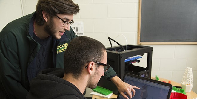 Two male students working at a laptop computer