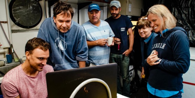 A group of marine scientists looking at a computer screen.