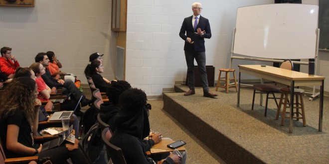 male teacher speaking emotively in front of a classroom of students