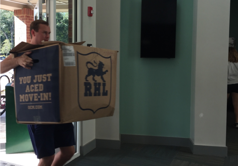 Man struggling to carry a box indoors