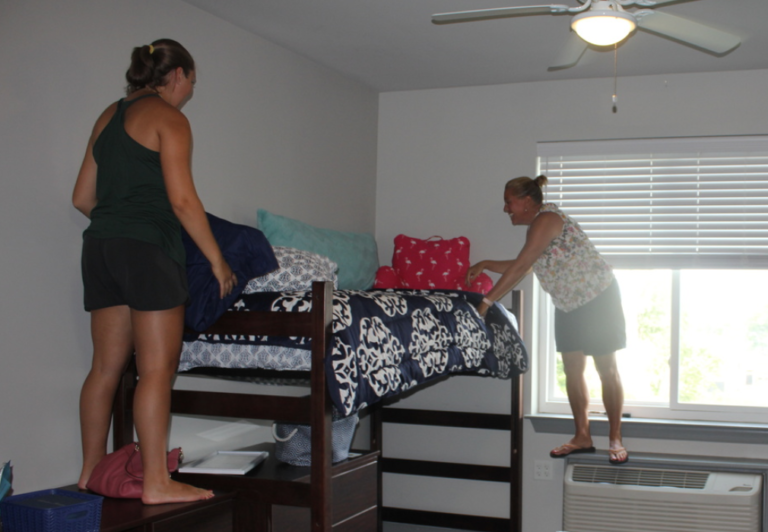A student and her mom making the students bed in her dorm