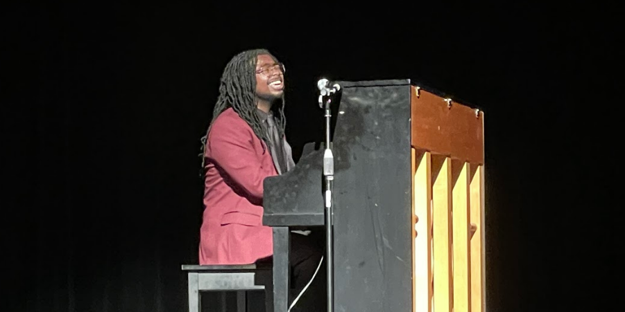 A male student musician singing while playing the piano.
