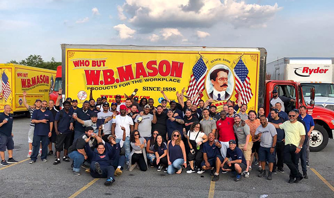 A large group of W.B. Mason employees standing together smiling in front of a W.B. Mason branded delivery truck