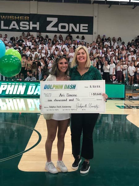 Ari Simone and trustee Audrey Moran pose with a large check in Historic Swisher Gymnasium