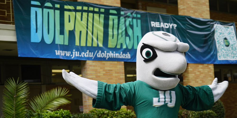 dunk'n poses in front of dolphin dash banner