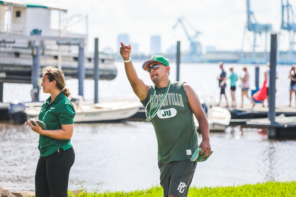 man plays cornhole along the river