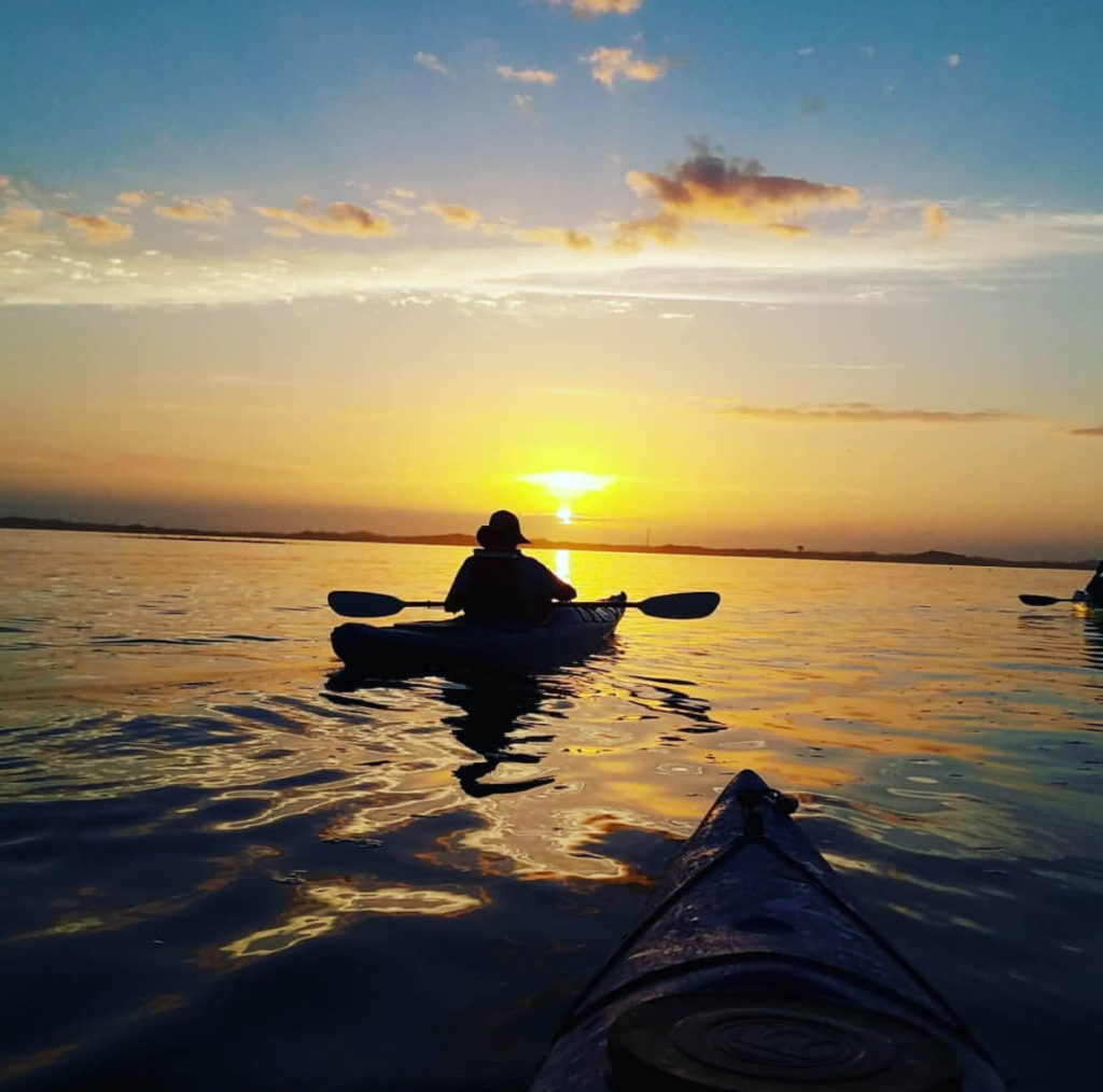 silhouette of a kayaker on the ater during sunset