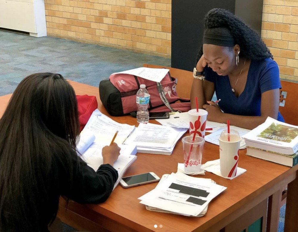 Two female students studying at the Carl Swisher Library before finals with snacks