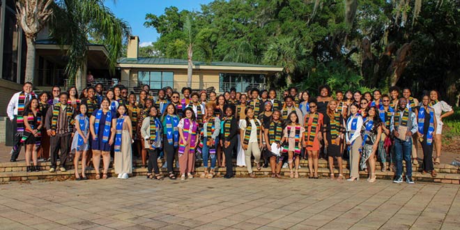 The students participating in Multicultural Graduation posed for a group photo behind the River House.