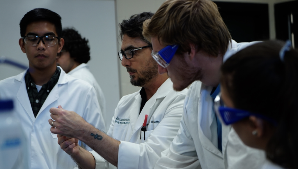 middle aged male chemist in lab coat working in classroom 