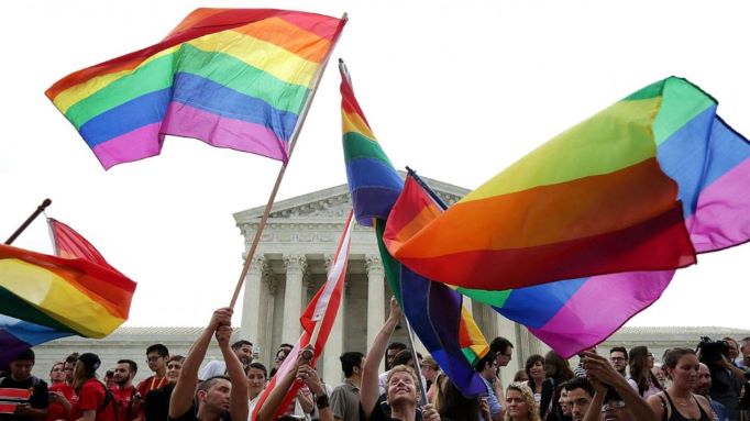 gay flags raised against a backdrop of people and the supreme court