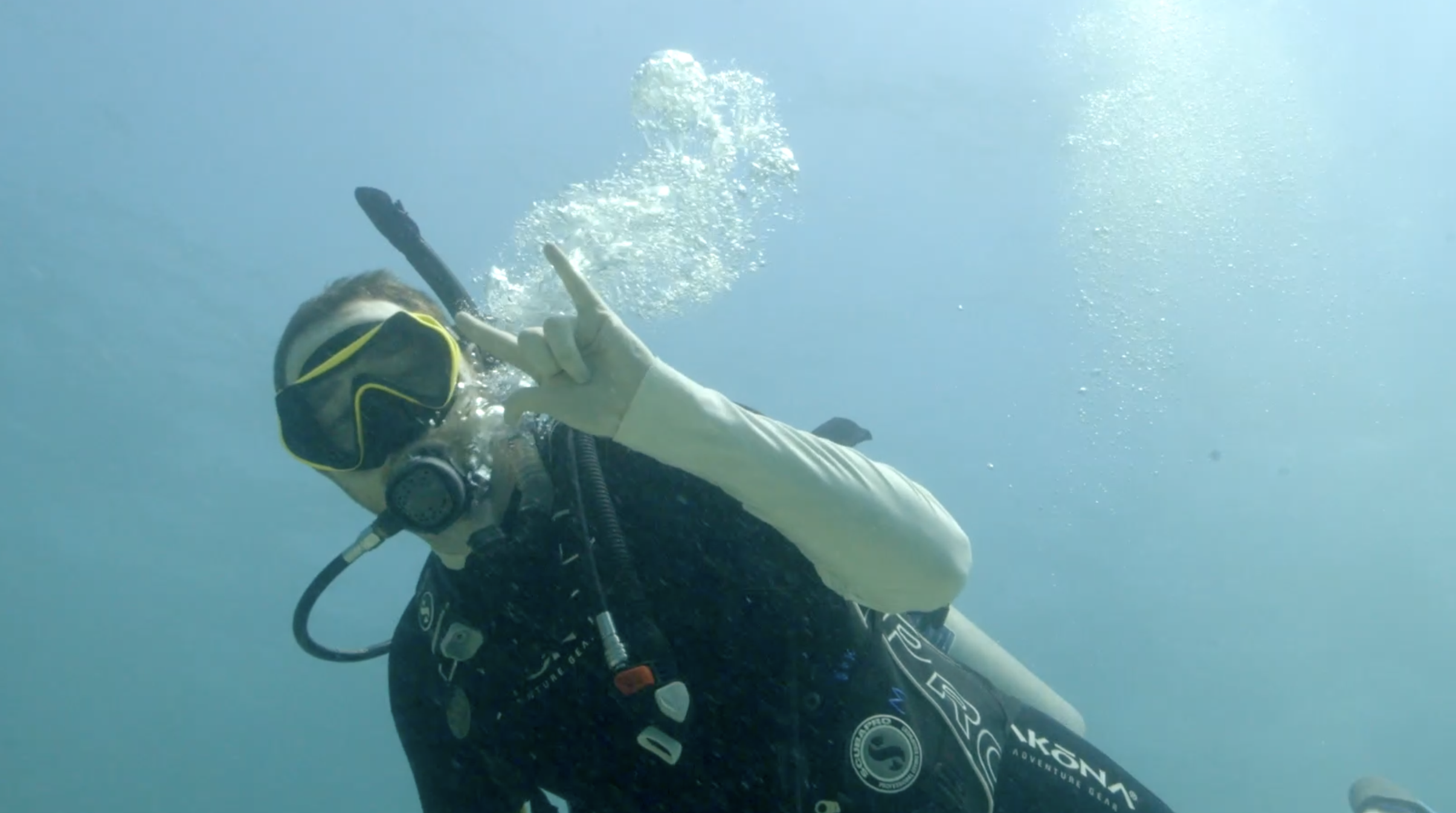 student gives phins up while scuba diving