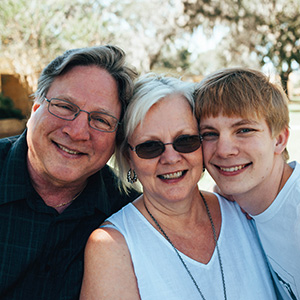 A student smiling with his parents. Click for parent and family information.