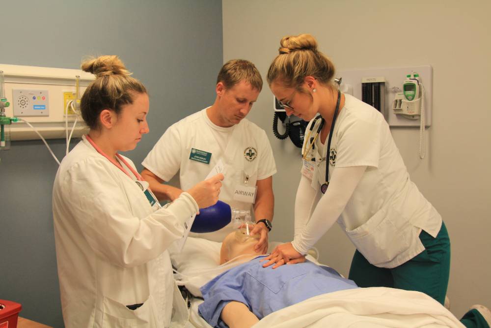 Three students practicing CPR in the health simulation center.