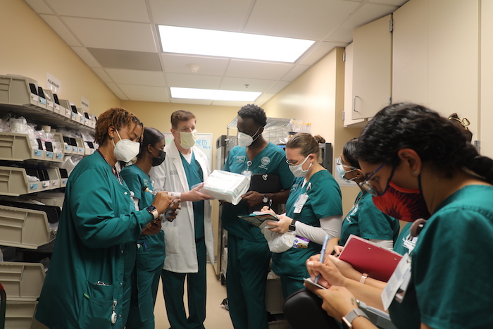 A nursing teacher with a group a students, teaching about healthcare supplies in a supply room.