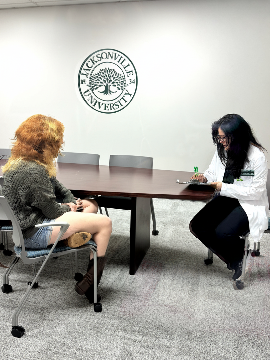 A nurse speaking with a patient while writing information on her tablet.