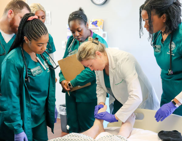 Students gathered around a simulation patient care at Keigwin School of Nursing