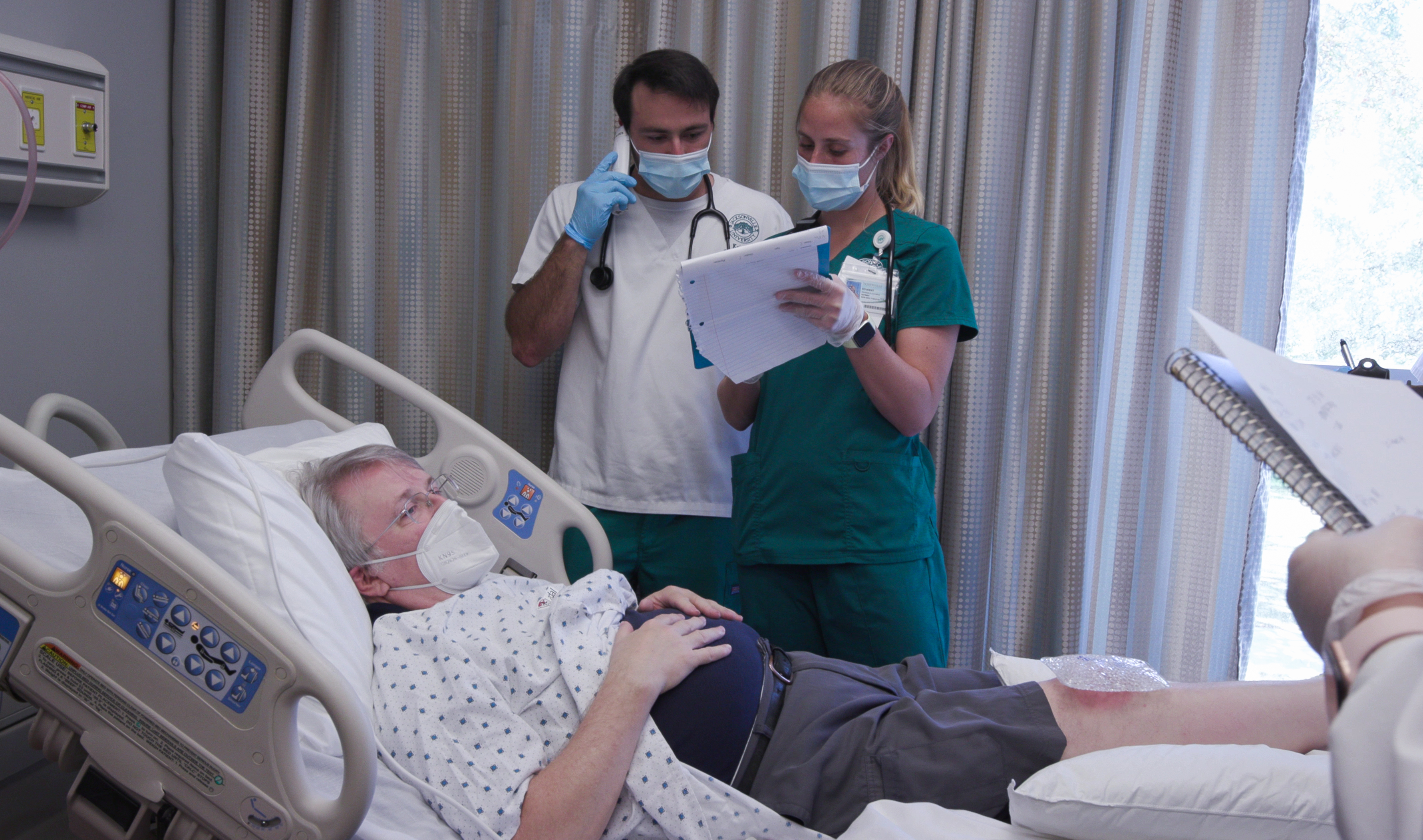 Two nursing students examining a patient