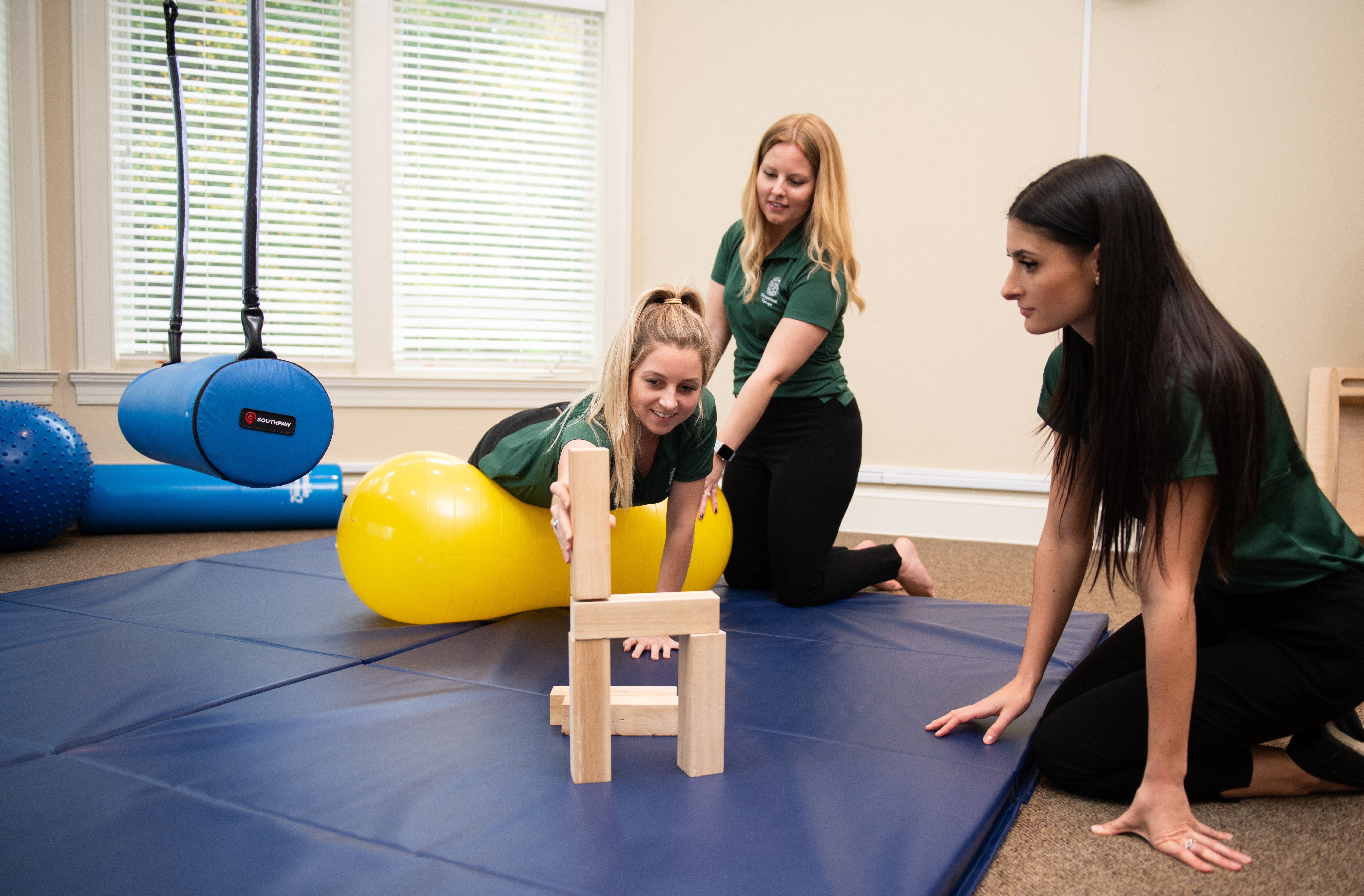 Three Occupational Therapy students demonstrating tools used during sessions