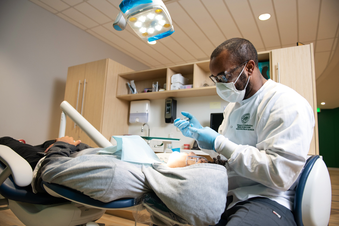 Orthodontic student practicing on a patient under supervision.